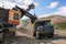 Excavator loads mountain soil into the bucket of a mining dump truck gold mining industry
