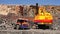 Excavator loads a stone in the heavy truck in the quarry mining granite