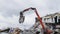 Excavator with manipulator dismantles debris of stadium