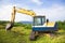 Excavator on the meadow with sky and ocean background