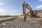 Excavator on a mountain of gravel at the construction site of a road