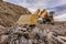 Excavator moving rocks on a site for processing and transformation