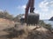 Excavator moving soil with lots of dust during excavation works on the rocky soils. Heavy machinery at earthmoving