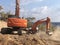 Excavator moving soil with lots of dust during excavation works on the rocky soils. Heavy machinery at earthmoving