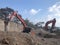 Excavator moving soil with lots of dust during excavation works on the rocky soils. Heavy machinery at earthmoving