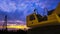 Excavator with pile driver and many precast concrete piles in construction site against colorful sunset sky