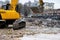 An excavator among a pile of garbage after dismantling an illegally constructed building.