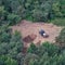 The excavator prepares the soil on the field in the forest among the trees for landscaping and agriculture, top view