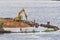 Excavator on the river bank with a jackhammer nozzle, embankment improvement work