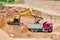 An excavator in a sand pit loads a dump truck with sand. Extraction of sand in an open pit. natural building materials