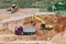 An excavator in a sand pit loads a dump truck with sand. Extraction of sand in an open pit. natural building materials