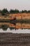 Excavator on the shore of a sand pit turning into a pond