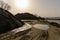 Excavator tracks in the sand with sunset over the pile of gravel in the distance