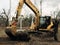 Excavator uprooting trees on land in countryside. Bulldozer clearing land from old trees and branches with dirt and trash. Backhoe