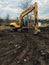 Excavator uprooting trees on land in countryside. Bulldozer clearing land from old trees, roots and branches with dirt and trash.