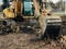 Excavator uprooting trees on land in countryside. Bulldozer clearing land from old trees, roots and branches with dirt and trash.