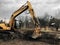 Excavator uprooting trees on land in countryside. Bulldozer clearing land from old trees, roots and branches with dirt and trash.