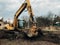 Excavator uprooting trees on land in countryside. Bulldozer clearing land from old trees, roots and branches with dirt and trash.