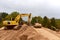 Excavator and Vibro Roller Soil Compactor at road construction and bridge projects in forest area. Heavy machinery for road work.