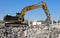 Excavator at work above a pile of debris in an industrial redevelopment area