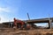 Excavator working at construction highway ramps and bridgeworks. Roundabout and traffic bridge construction. Road work