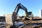 Excavator working at construction site on earthworks. Backhoe digging building foundation. Paving out sewer line. Heavy machinery