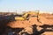 Excavator working at construction site on earthworks. Backhoe digs ground in pit for laying concrete sewer wells and sewage pipes