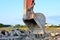 Excavator working in a construction site. Large metal iron ladle. Crusher bucket for crushing concrete.