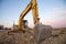 Excavator working at construction site on sunset background. Backhoe digs gravel and concrete crushing. Recycling old concrete