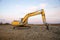 Excavator working at construction site on sunset background. Backhoe digs gravel and concrete crushing. Recycling old concrete