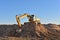 Excavator working on earthmoving at open pit mining. Yellow Backhoe digs sand and gravel in quarry. Heavy Construction Equipment