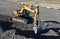 Excavator working at open pit mining. Backhoe digs gravel in sand quarry on blue sky background. Recycling old asphalt at a