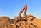 Excavator works on a construction site during excavation work against a blue sky background. Open pit development for sand