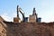 Excavators during earthworks at construction site. Backhoe the digging pit for construct building foundation. Paving out sewer