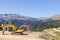 Excavators parked in a mountain valley on a sunny day. Construction of a ski track.