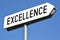 Excellence - metal, white signpost, sky in background.