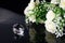 Excellent diamond of the first water and bouquet of white roses with reflection on black mirror background close up view. Jewelry