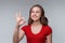 Excellent job. Attractive young brunette woman in red t shirt showing OK sign and smiling, give positive reply