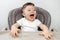 Excited adorable baby boy play in high chair. Baby laughing.