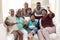 Excited african american parents, grandparents and grandchildren on couch watching tv and cheering