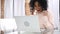 Excited Afro-American woman celebrating success while working on laptop, sitting on couch