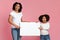 Excited Afro mother and daughter holding and pointing at white placard