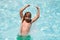 Excited amazed child splashing in swimming pool. Swim water sport activity on summer vacation with child.