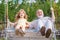 Excited amazed old grandfather and young child grandson swinging in garden outdoors. Grand dad and grandson sitting on