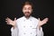 Excited amazed young bearded male chef cook or baker man in white uniform shirt posing isolated on black wall background