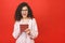 Excited amazed young beautiful woman with tablet pc. Happy girl in white shirt using tablet computer, isolated on red background