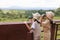 Excited asian child girls looking through binocular searching for animal in savannah green forest.