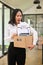 Excited Asian female office worker carrying her belonging, quitting a job