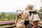 Excited asian kid looking through binocular searching for animal with her mother in savannah green forest.