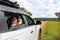 Excited asian kid looking through binocular searching for animal while traveling with car in tropical Savannah forest.